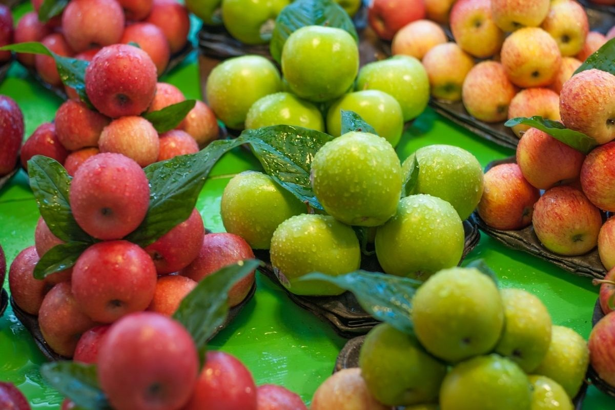 Zöld, piros és sárga almák kupacokba rendezve